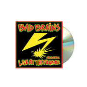Image of a cd sleeve and silver cd against a white background. The cd sleeve is a Photo of the bad brains- live at the fillmore album artwork. The artwork has a red border and is filled with black. On top of the background it says Bad brains at the top in red with a yellow outline and outlined again in green. At the bottom in red with yellow and green outline it says 3/20/1982 live at the fillmore. The middle of the artwork features a yellow lightning bolt.
