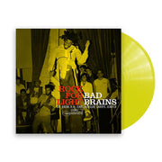 photo of a bad brains rock for light vinyl sleeve and yellow vinyl against a white background. The album cover is a yellow photograph that shows the band performing for a crowd. The singer is front and center, jumping in the air. The guitarist and fans can be seen in the background. At the bottom of the image in red letters it says rock for light. Next to that in white it says bad brains. Below this in white text it says "Dr. Know, H.R., Earl Hudson, Darryl Jenifer. "1983 stereo punk note". 